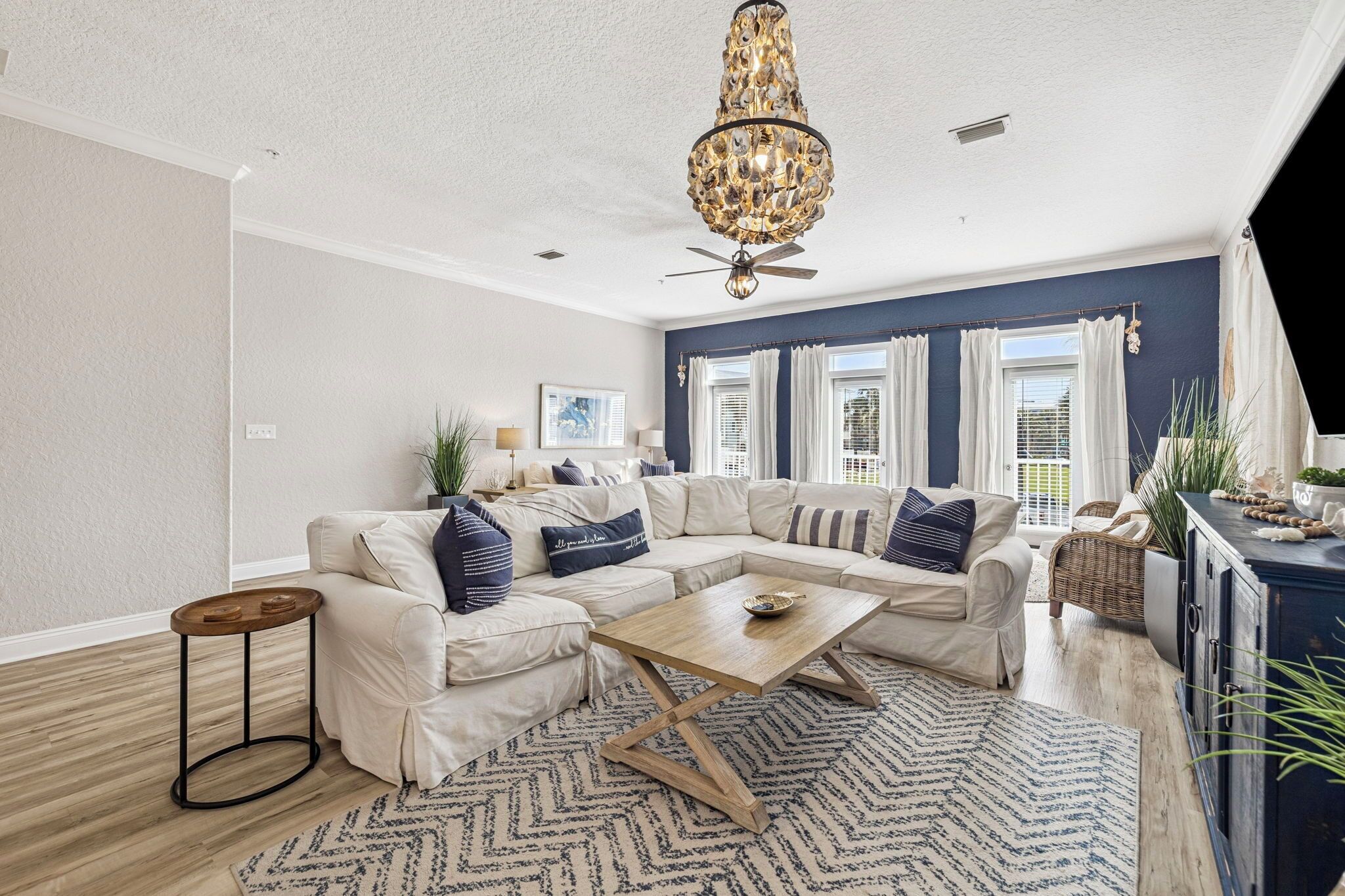 A living room with a sectional sofa, a wooden coffee table, and a chandelier.