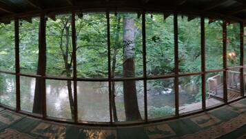 A room with large windows offering a view of a forested area.