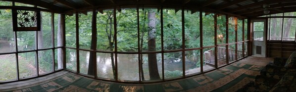 A room with large windows offering a view of a forested area. - Turtle Place on Terrapin Creek (Piedmont)