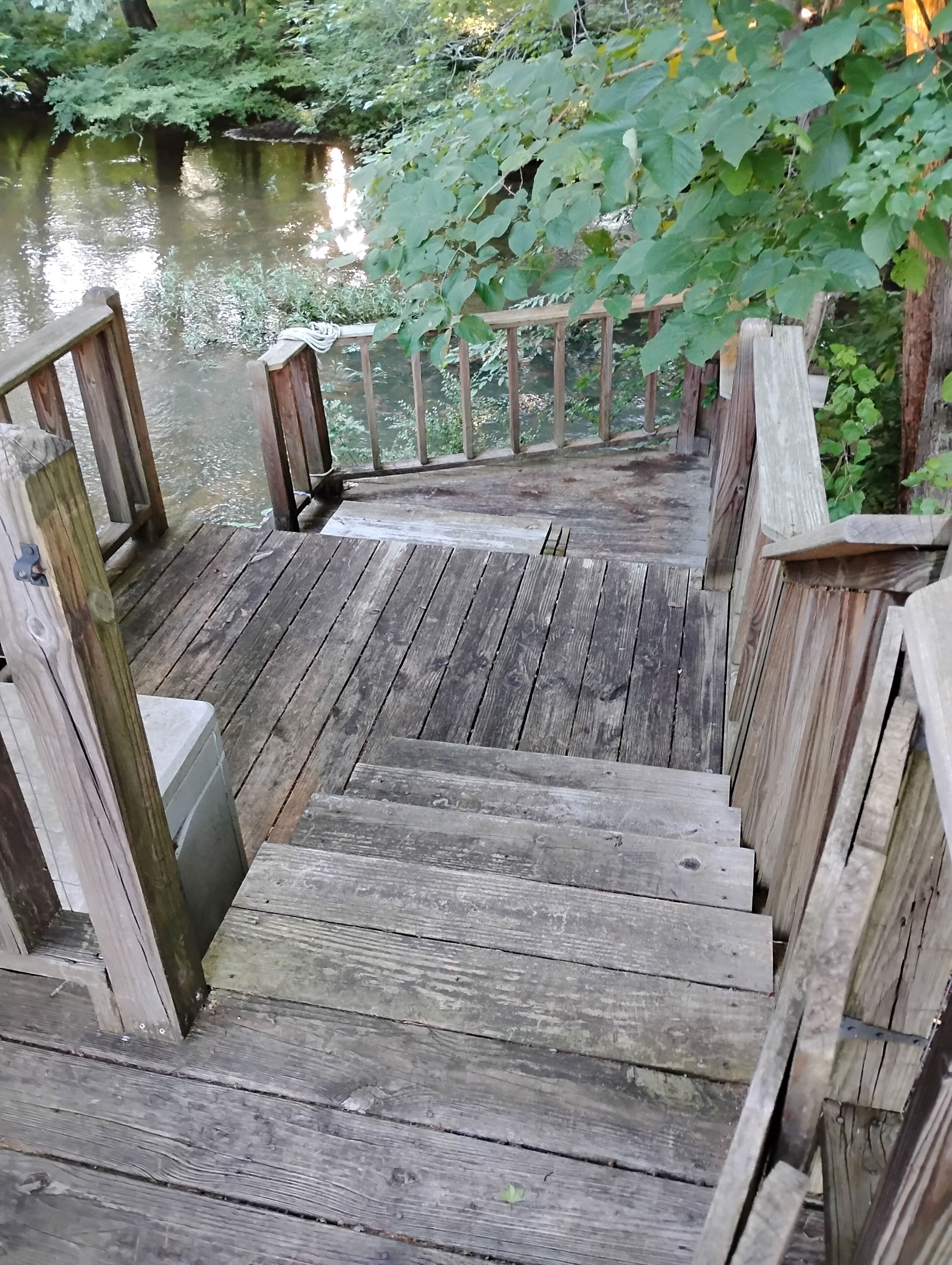 Una terraza de madera que da a un cuerpo de agua, rodeada de vegetación.