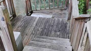 Una terraza de madera que da a un cuerpo de agua, rodeada de vegetación.