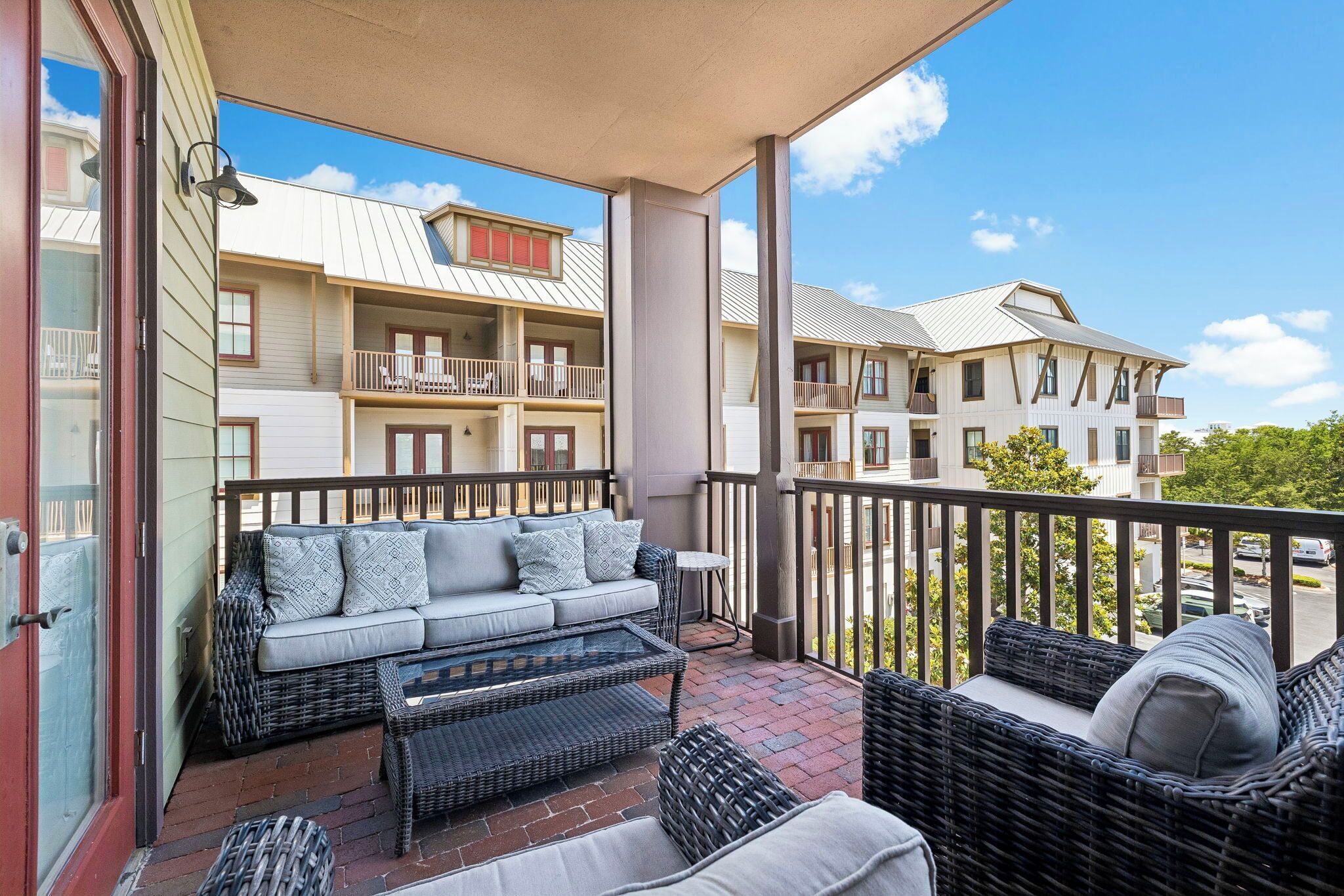 A balcony with wicker furniture, a glass door, and a view of neighboring buildings.