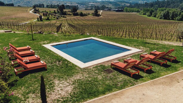 A pool surrounded by lounge chairs and a vineyard in the background. - Casa Villae Relais & Châteaux - The most charming house in the Dão region (Silvã de Cima)