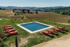 A pool surrounded by lounge chairs and a vineyard in the background. - Casa Villae Relais & Châteaux - The most charming house in the Dão region (Silvã de Cima)