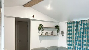 Una sala de estar moderna con un sofá seccional, una mesa de comedor de madera y un estante empotrado con elementos decorativos.