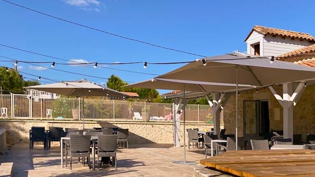 Un patio al aire libre con piso de piedra, mobiliario exterior y sombrillas.