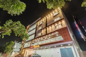 Un hotel de varios pisos con un cartel que dice 'Hotel Rasbello', balcones y un garaje.