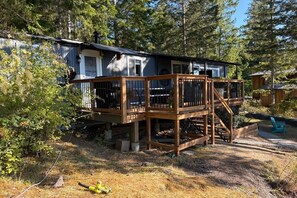 A cabin with a wooden deck, surrounded by trees.