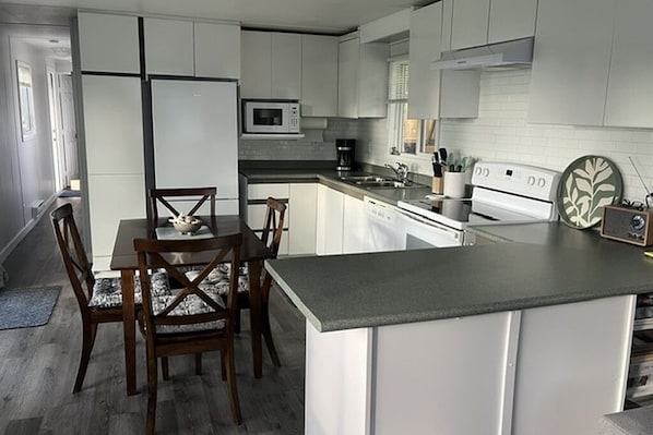 Una cocina moderna con armarios blancos, una isla central, un microondas, una cafetera y una estufa.