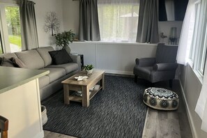 Una sala de estar con sofá, sillón, mesa de centro y reposapiés.
