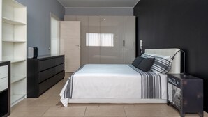 Ein modernes Schlafzimmer mit einem Bett, einem Schminktisch, einem Kleiderschrank und einem kleinen Schrank.