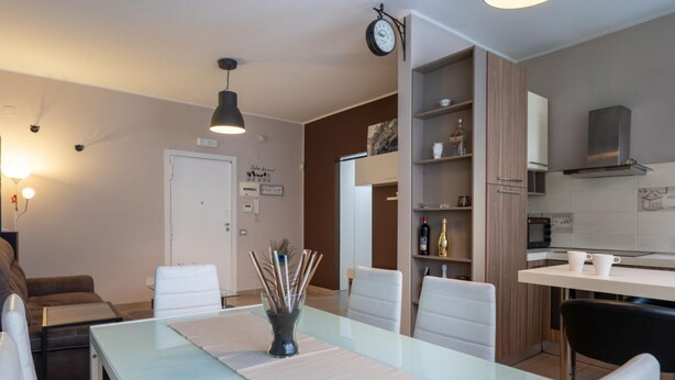 Eine moderne Küche mit Mikrowelle, Backofen und Schränken. Es gibt einen Essbereich mit einem Glastisch und Stühlen, sowie eine Wohnbereich mit einer Couch und einem Couchtisch.