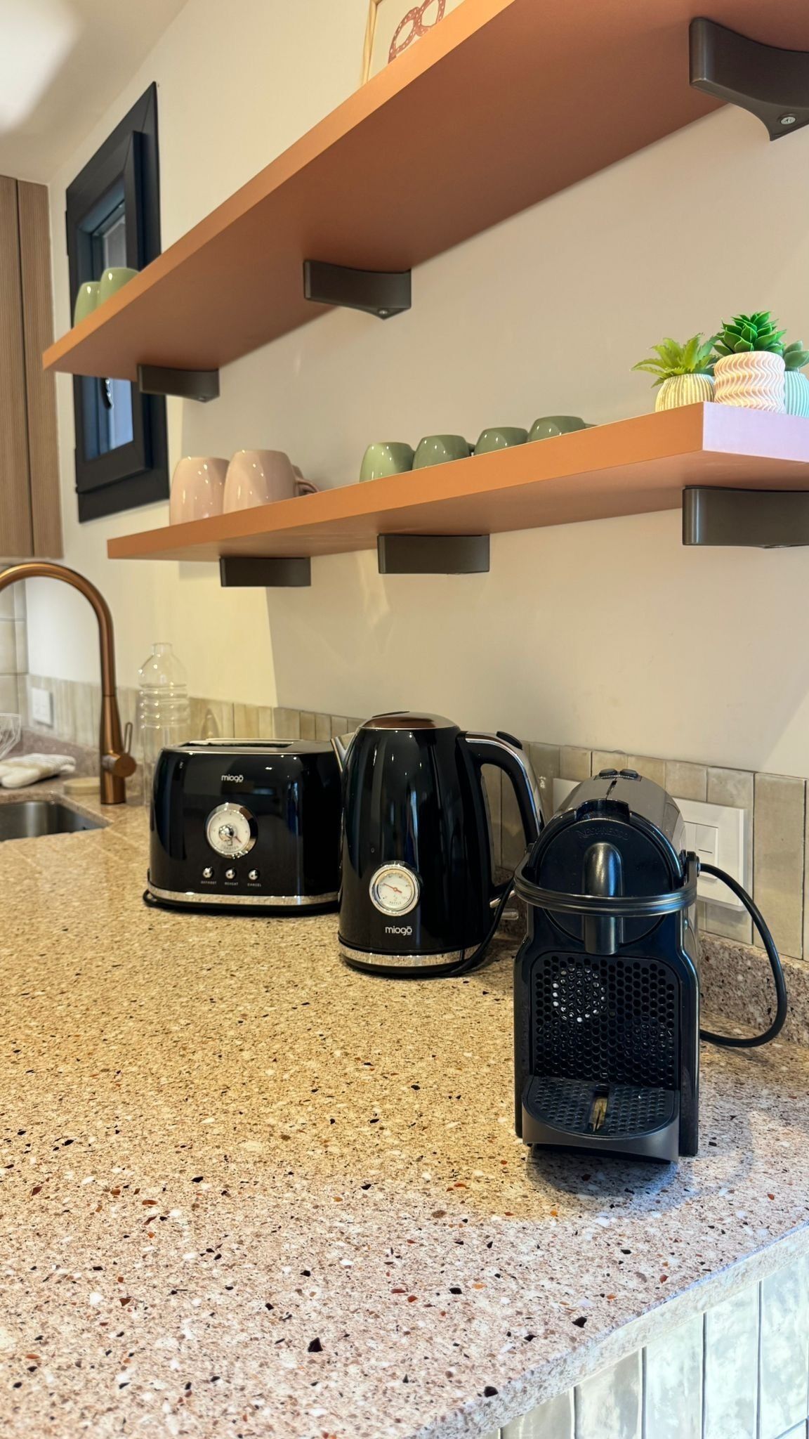 Een keuken met een granieten aanrecht, een koffiezetapparaat, een waterkoker en een broodrooster.