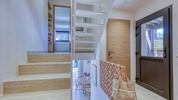 Un intérieur moderne avec un escalier, une porte en bois et une vue à travers une porte vitrée.