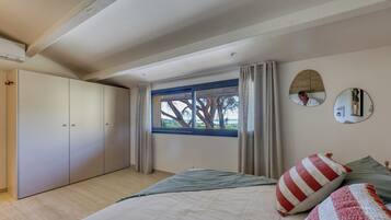 Une chambre à coucher avec un lit, une armoire, une fenêtre avec des rideaux et un miroir sur le mur.