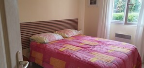 A bedroom with a bed, a window, and a radiator. - House with a garden (fenced), in a very quiet area, with a view of the forest (Lacanau)