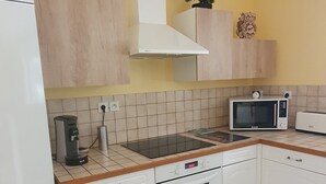 Keittiössä on valkoiset kaapit, mikroaaltouuni, liesi ja kahvinkeitin.