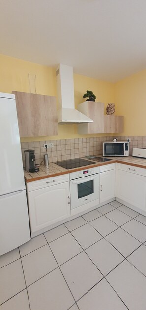 A kitchen with white cabinets, a microwave, a stove, and a coffee maker. - House with a garden (fenced), in a very quiet area, with a view of the forest (Lacanau)