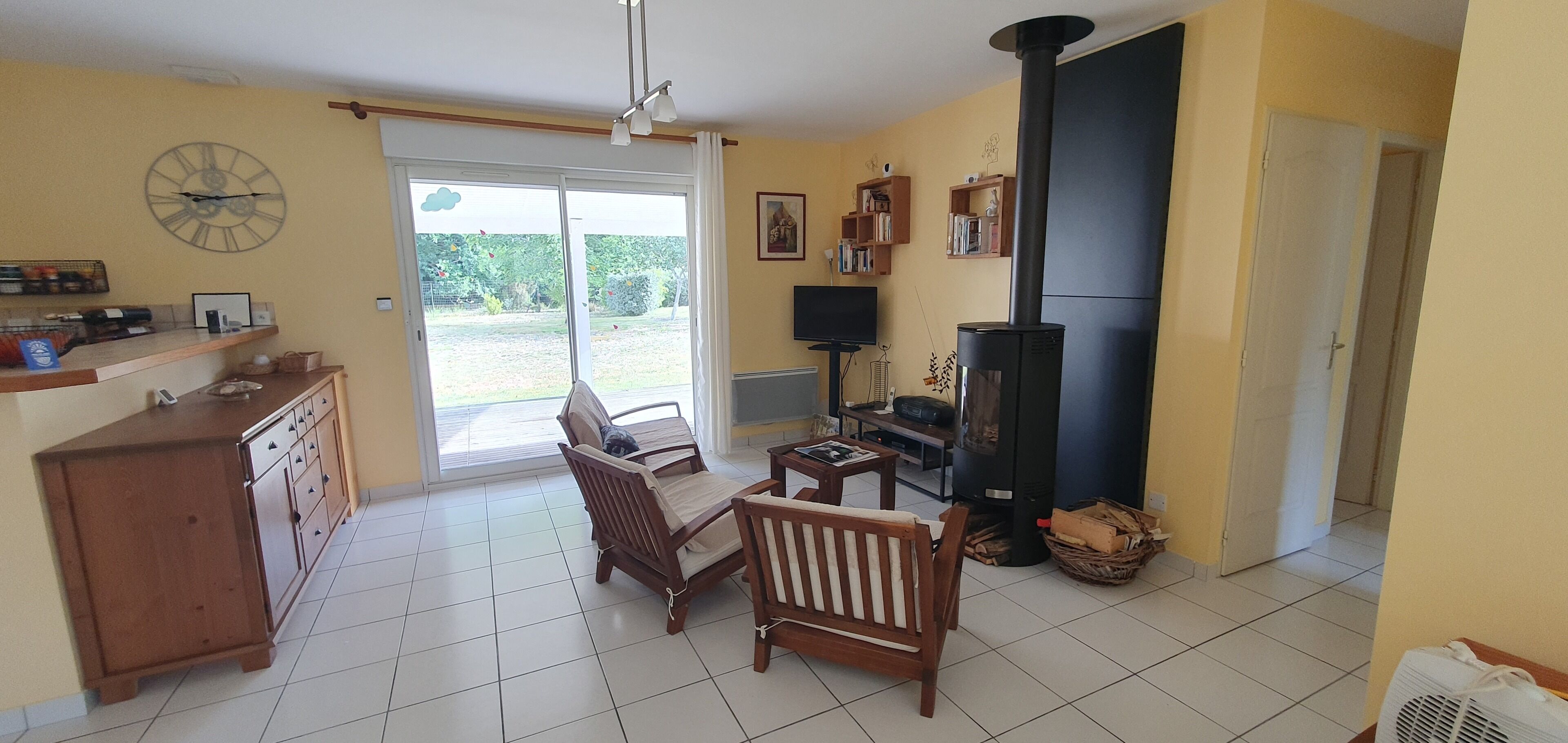 A living room with a fireplace, a sofa, a TV, and a dining area with a cabinet.