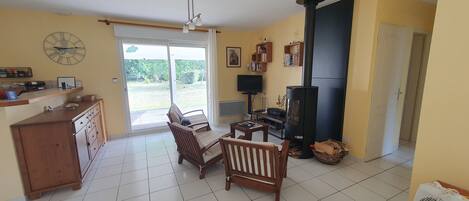 A living room with a fireplace, a sofa, a TV, and a dining area with a cabinet.