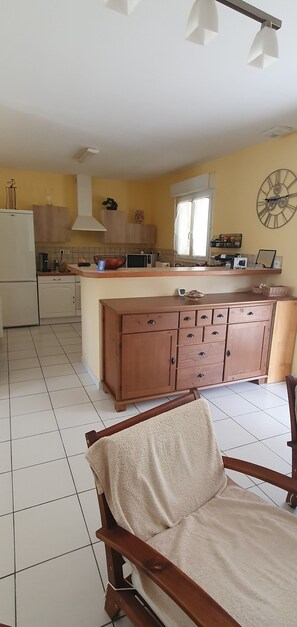 A kitchen with a central island, wooden cabinets, a white refrigerator, and a clock on the wall. - House with a garden (fenced), in a very quiet area, with a view of the forest (Lacanau)