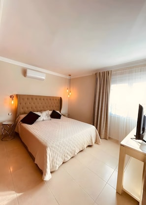 Un dormitorio con cama, mesita de noche, lámpara, aire acondicionado y televisión.