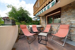 A patio with four lounge chairs and a stone wall. - Apartment for 7 Guests – Châtel – Terrace, Parking, Near the Slopes (Châtel)
