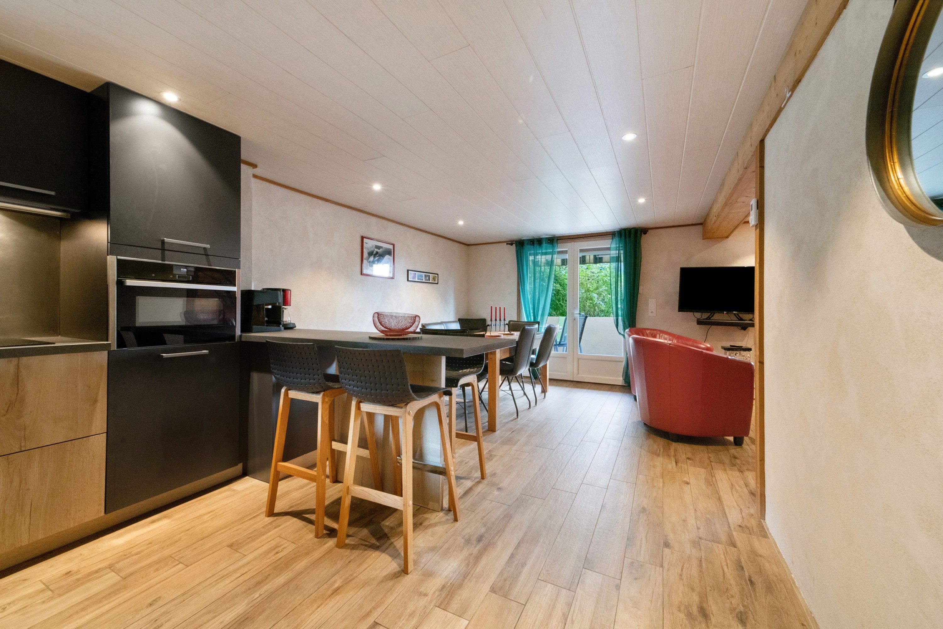 Una cocina moderna con una isla central, sillas de madera y una silla roja.