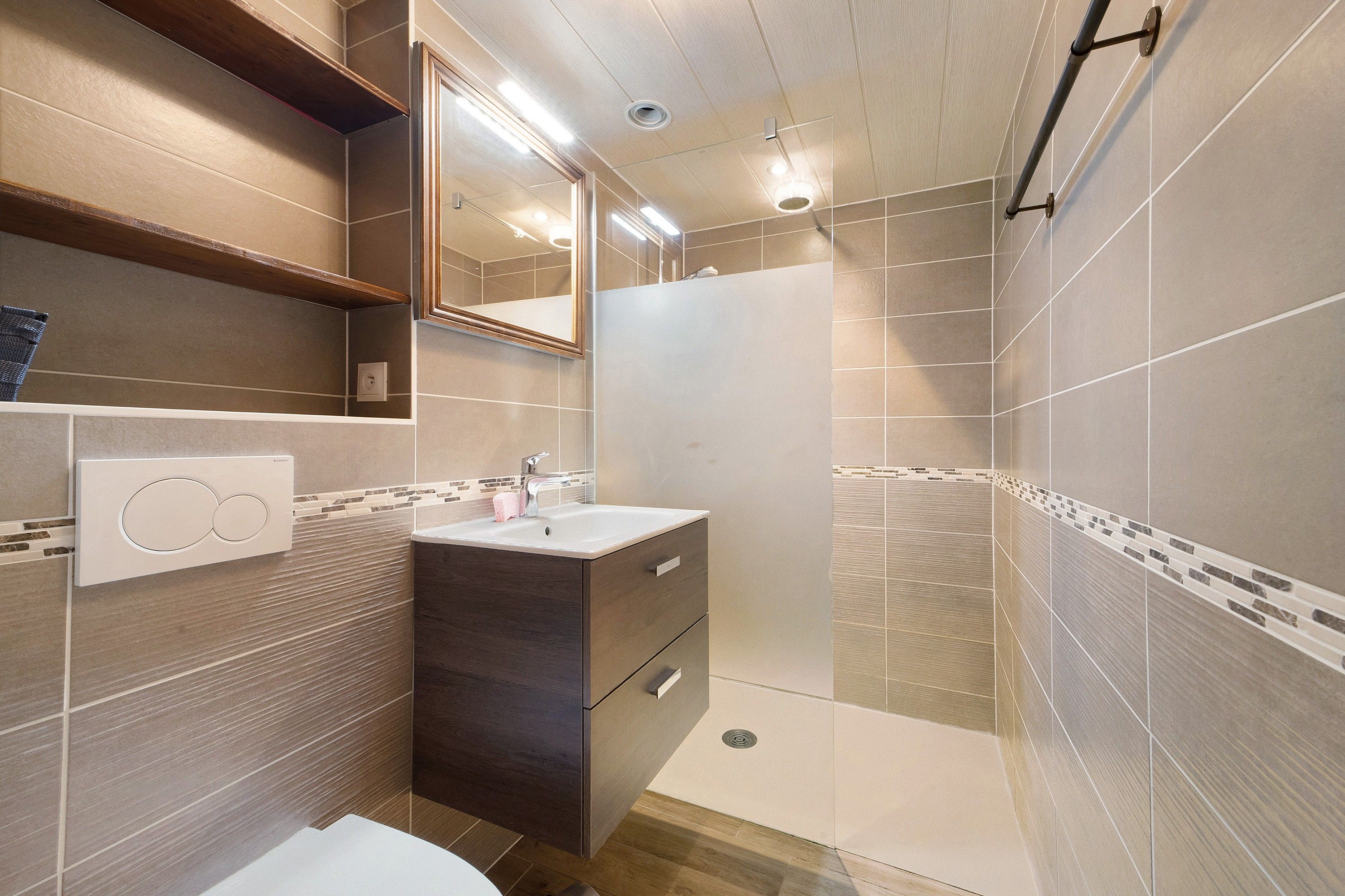 A modern bathroom with a shower, a sink, and a mirror.