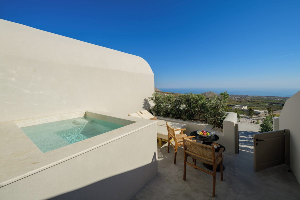 Terraza en la azotea con jacuzzi, sillas de mimbre y una mesa con fruta.