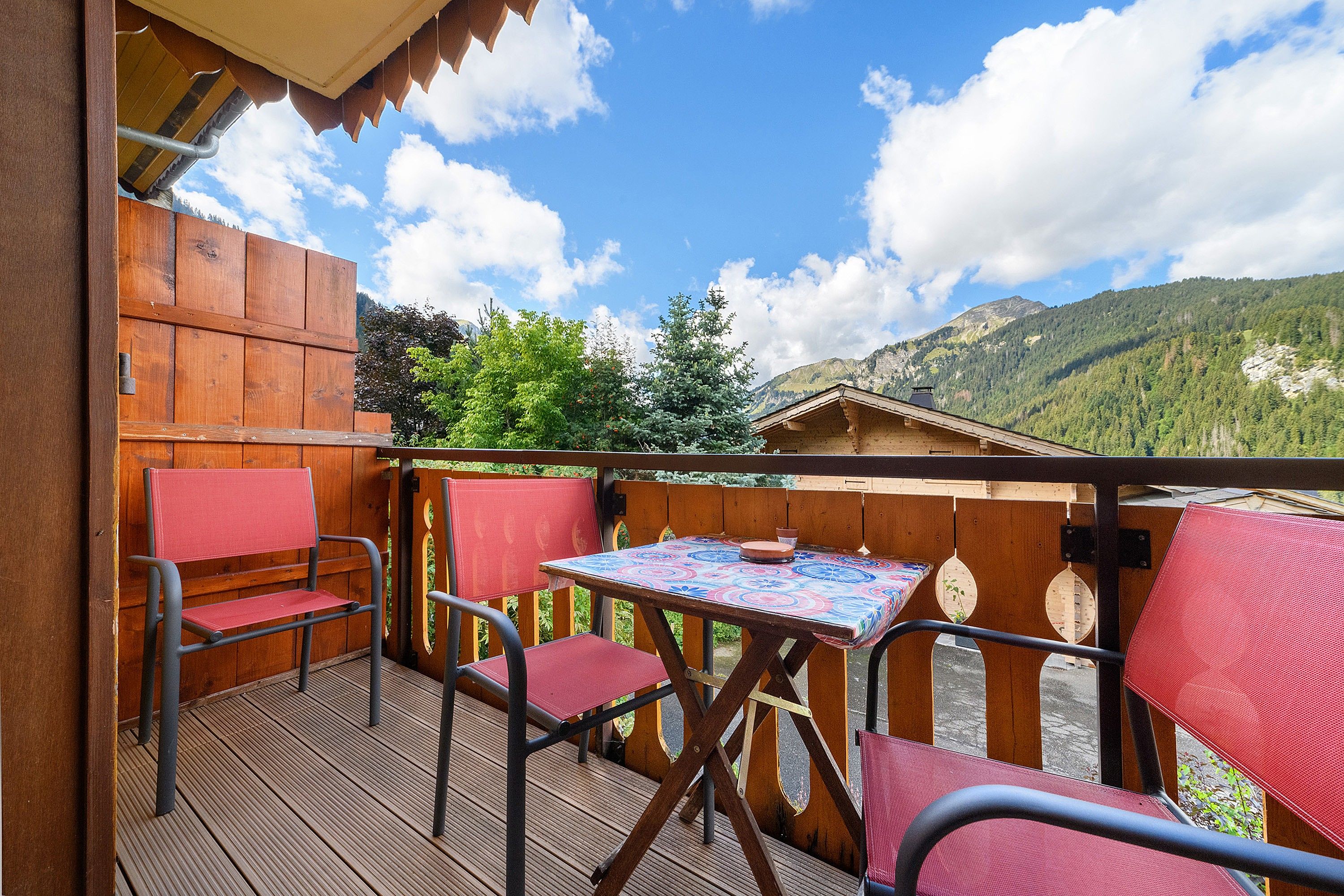 Eine Holzterrasse mit Tisch und Stühlen mit Blick auf eine Berglandschaft.