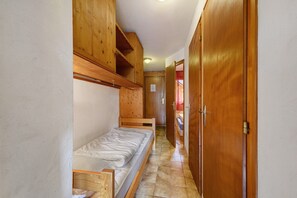 A narrow hallway with wooden walls and a single bed with a wooden headboard. - 2-Room Apartment for 4 – Châtel – Balcony, Parking, Near the Slopes (Châtel)