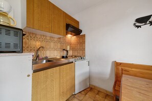 A compact kitchen with wooden cabinets, a built-in oven, and a small refrigerator. - 2-Room Apartment for 4 – Châtel – Balcony, Parking, Near the Slopes (Châtel)