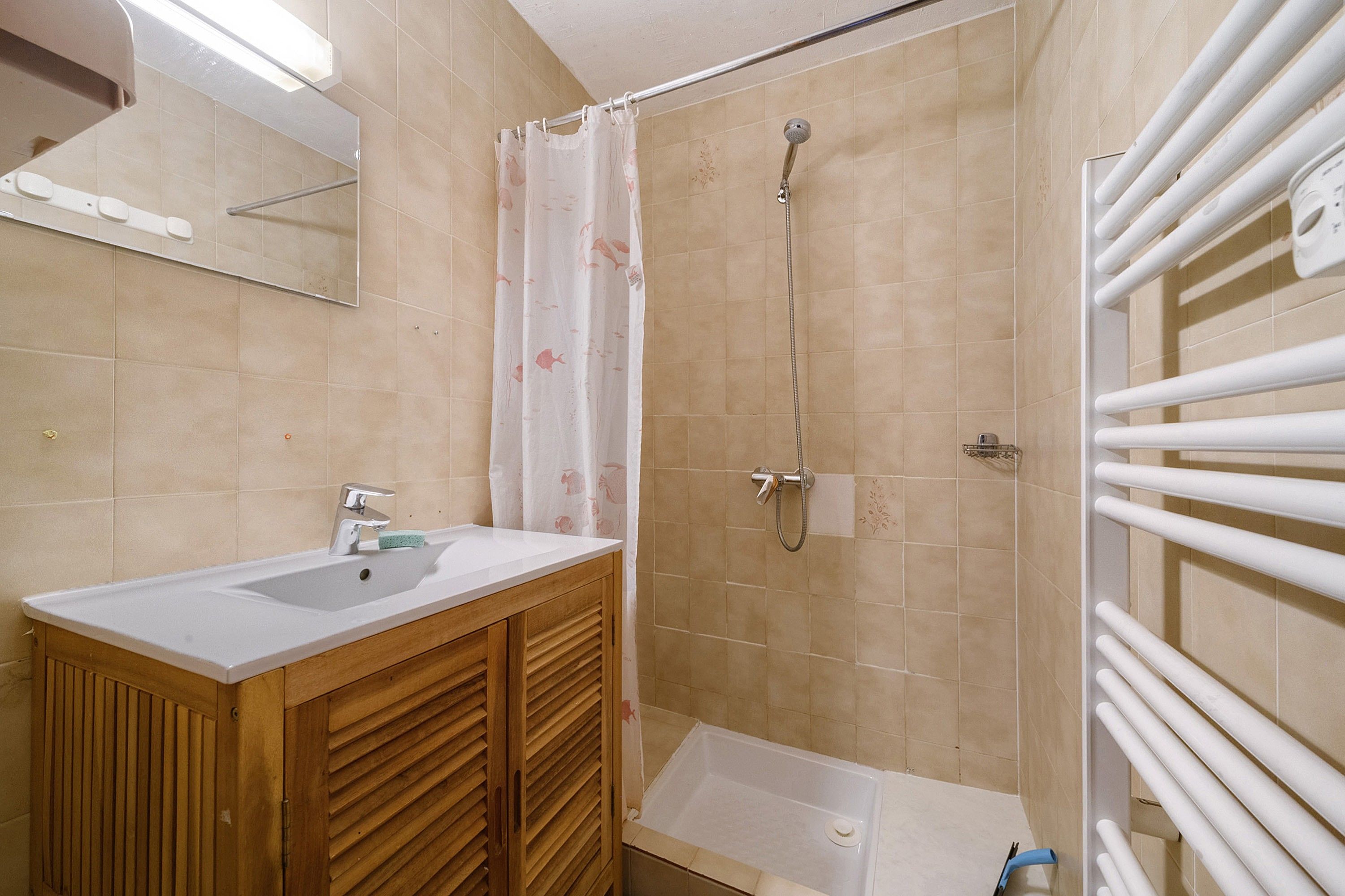 A bathroom with a shower, a sink, and a mirror.