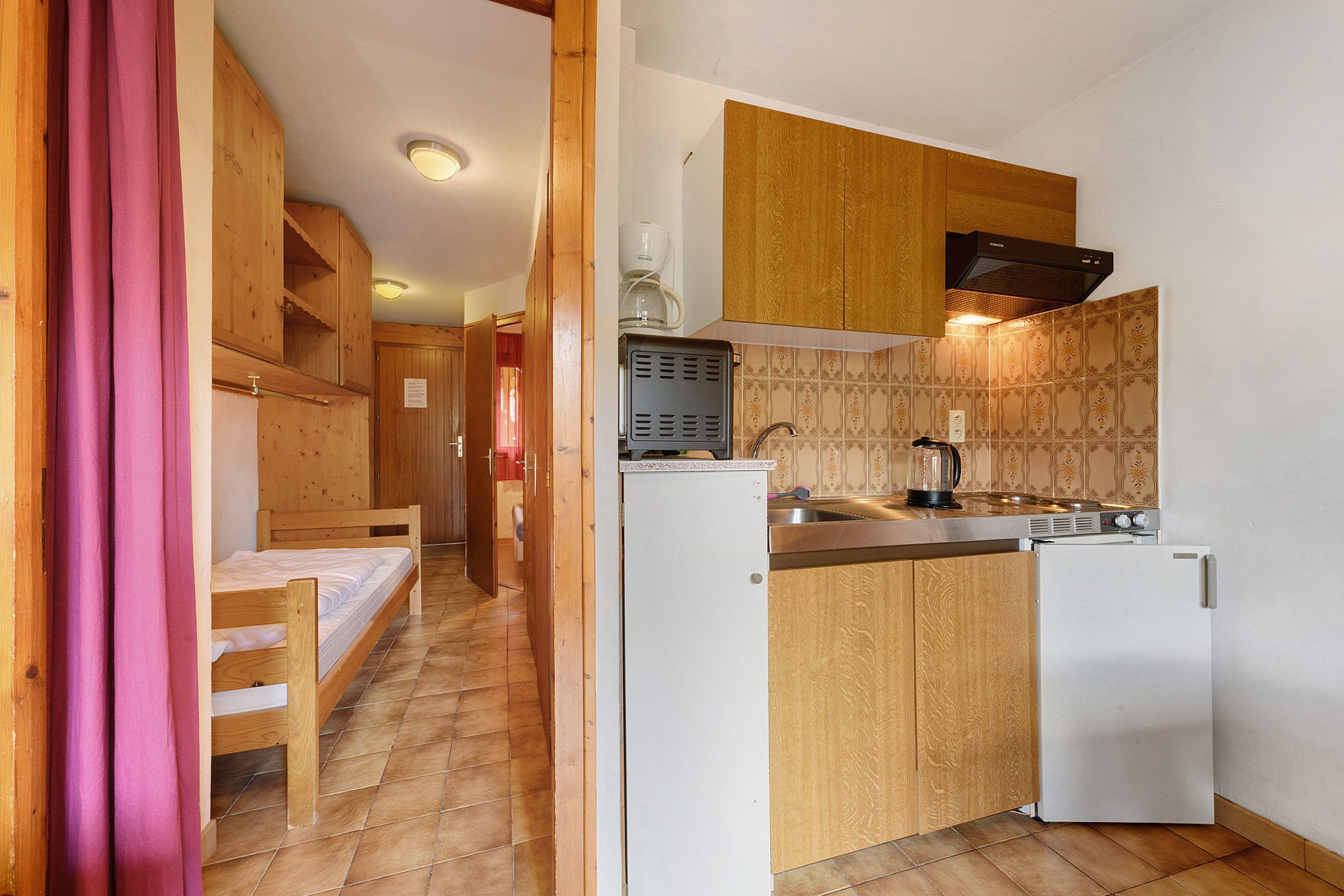 A compact kitchen with wooden cabinets, a built-in stove, and a small refrigerator.