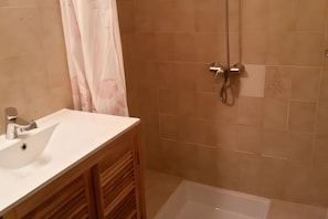 Une salle de bain avec une douche, un lavabo et une baignoire.