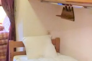A single bed with a wooden headboard, a white pillow, and a wooden nightstand. - 2-Room Apartment for 4 – Châtel – Balcony, Parking, Near the Slopes (Châtel)