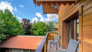 Ein Holzbalkon mit Metallgeländer, einem Stuhl und Blick auf eine Berglandschaft.