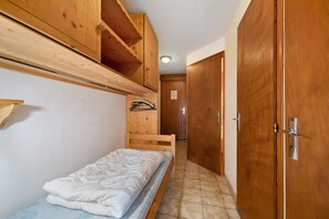 A narrow hallway with a single bed, wooden wardrobe, and a wooden shelf above the bed. - Apartment for 5 in Châtel – Near Slopes, Balcony, Free Private Parking (Châtel)