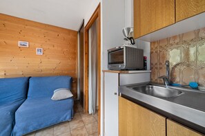 A compact kitchen with wooden cabinets, a built-in microwave, and a sink. - Apartment for 5 in Châtel – Near Slopes, Balcony, Free Private Parking (Châtel)