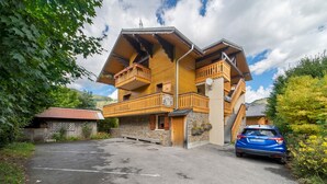 Eine mehrstöckige Holzhütte mit Balkonen, einer Stein-Fassade und einem Parkplatz.