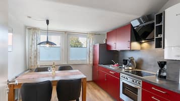 Una cocina compacta con una mesa, sillas, estufa y armarios.