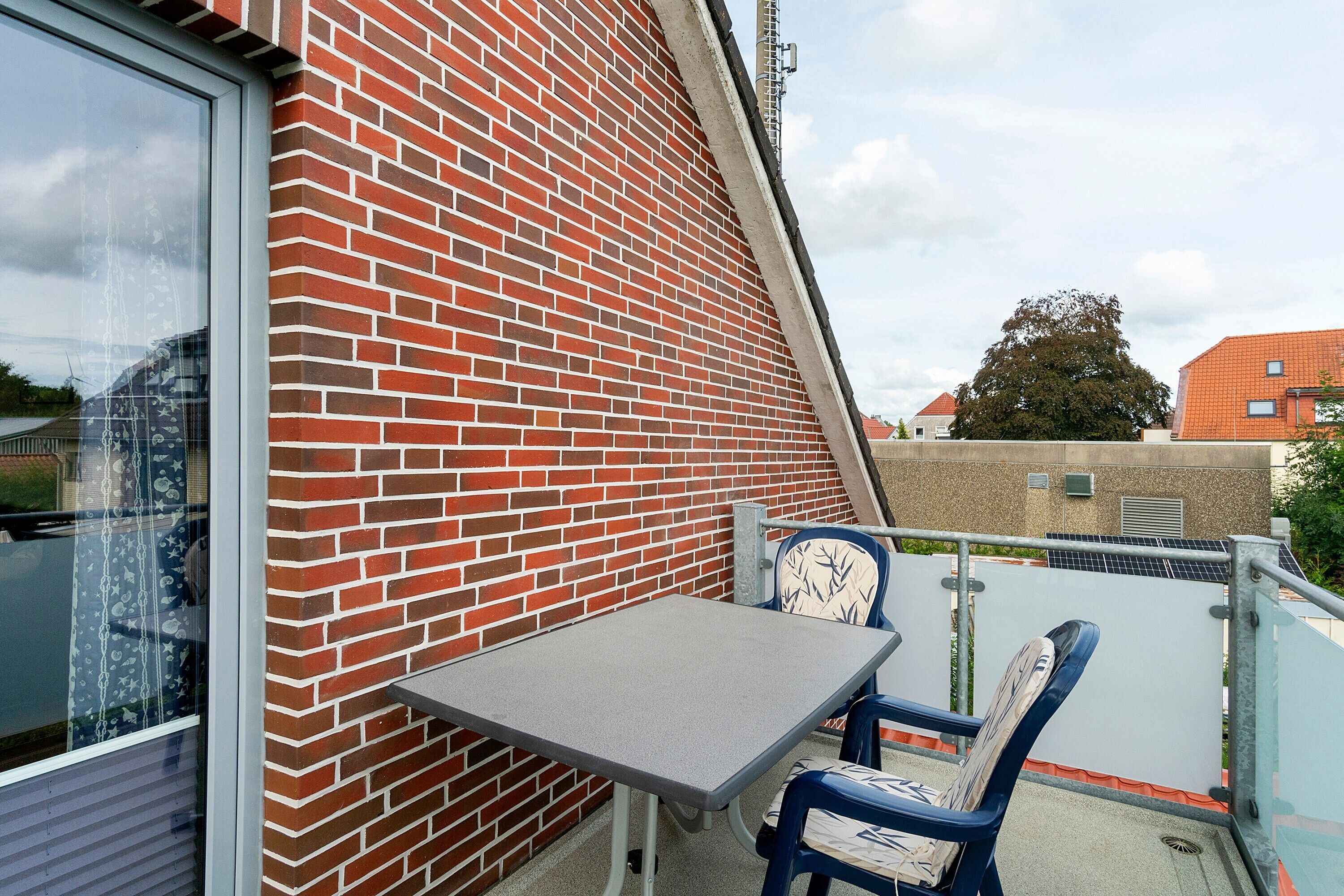 Ein Balkon mit einer Ziegelwand, einem Tisch und zwei Stühlen.