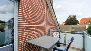 Ein Balkon mit einer Ziegelwand, einem Tisch und zwei Stühlen.