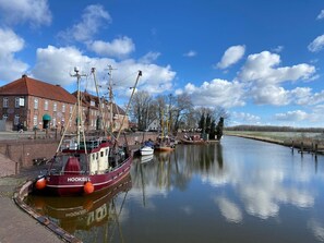 Un canal bordé de bateaux amarrés, un bâtiment en briques rouges et un ciel dégagé.