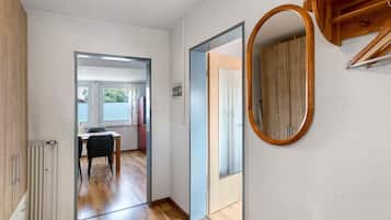 Ein Flur mit Holzboden, einem Heizkörper, einem Esstisch mit Stühlen und einem Spiegel an der Wand.