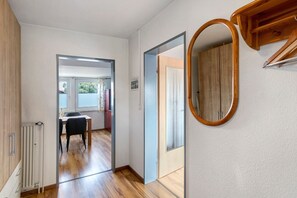Ein Flur mit Holzboden, einem Heizkörper, einem Esstisch mit Stühlen und einem Spiegel an der Wand.
