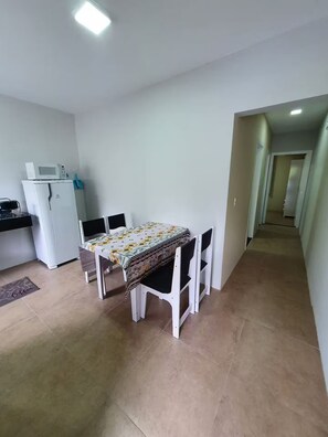 A dining area with a table and chairs, a microwave, and a refrigerator.