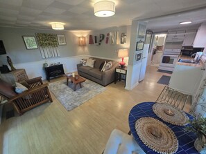Ein Wohnzimmer mit einer Couch, einem Couchtisch und einem Essbereich mit blauer Tischdecke.
