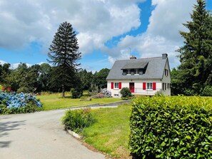 A house with a sloped roof, a chimney, and a red door. - Detached house with very large private garden in a quiet location (Plouguernevel)